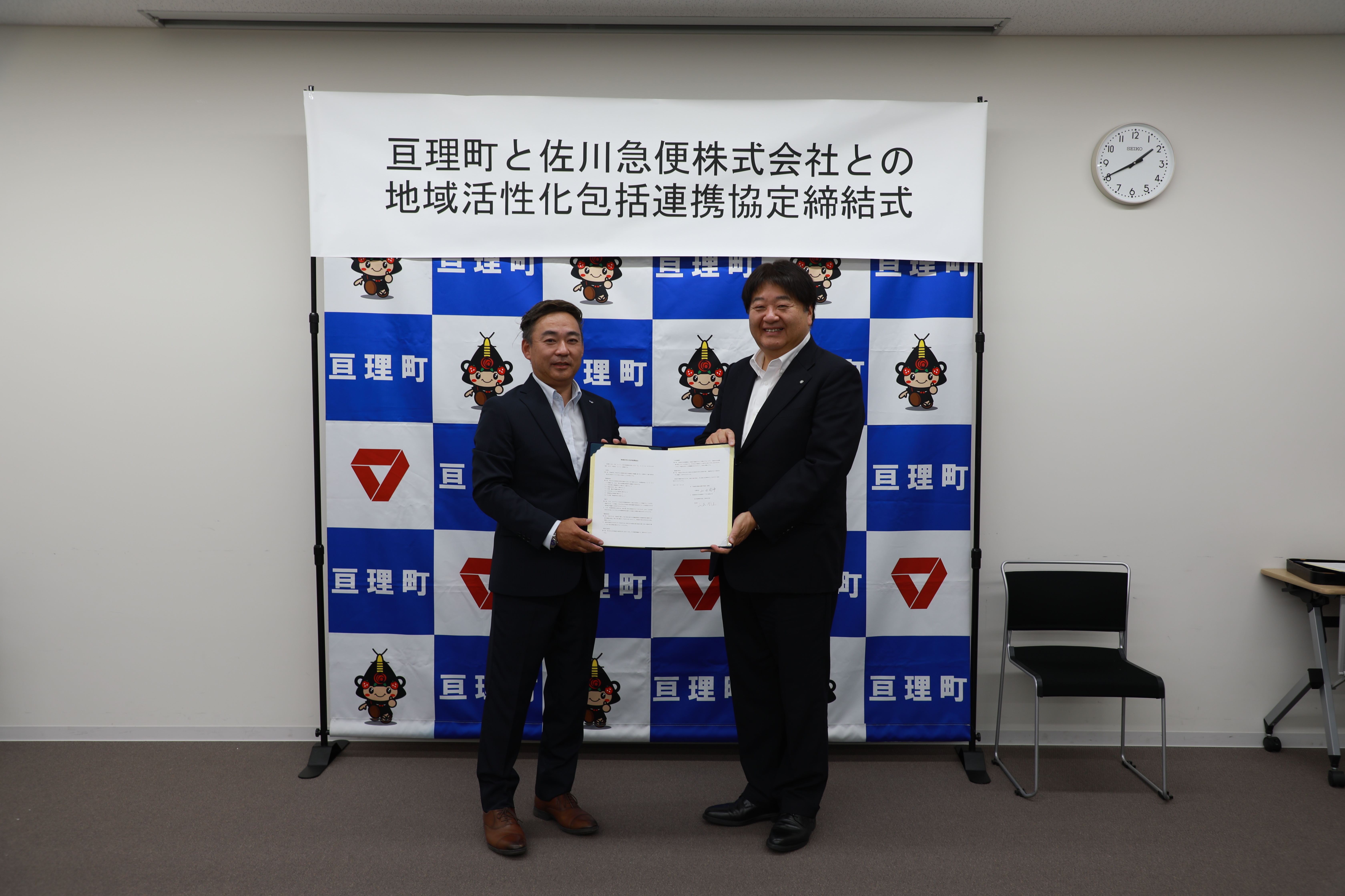 協定書を持つ支店長と町長